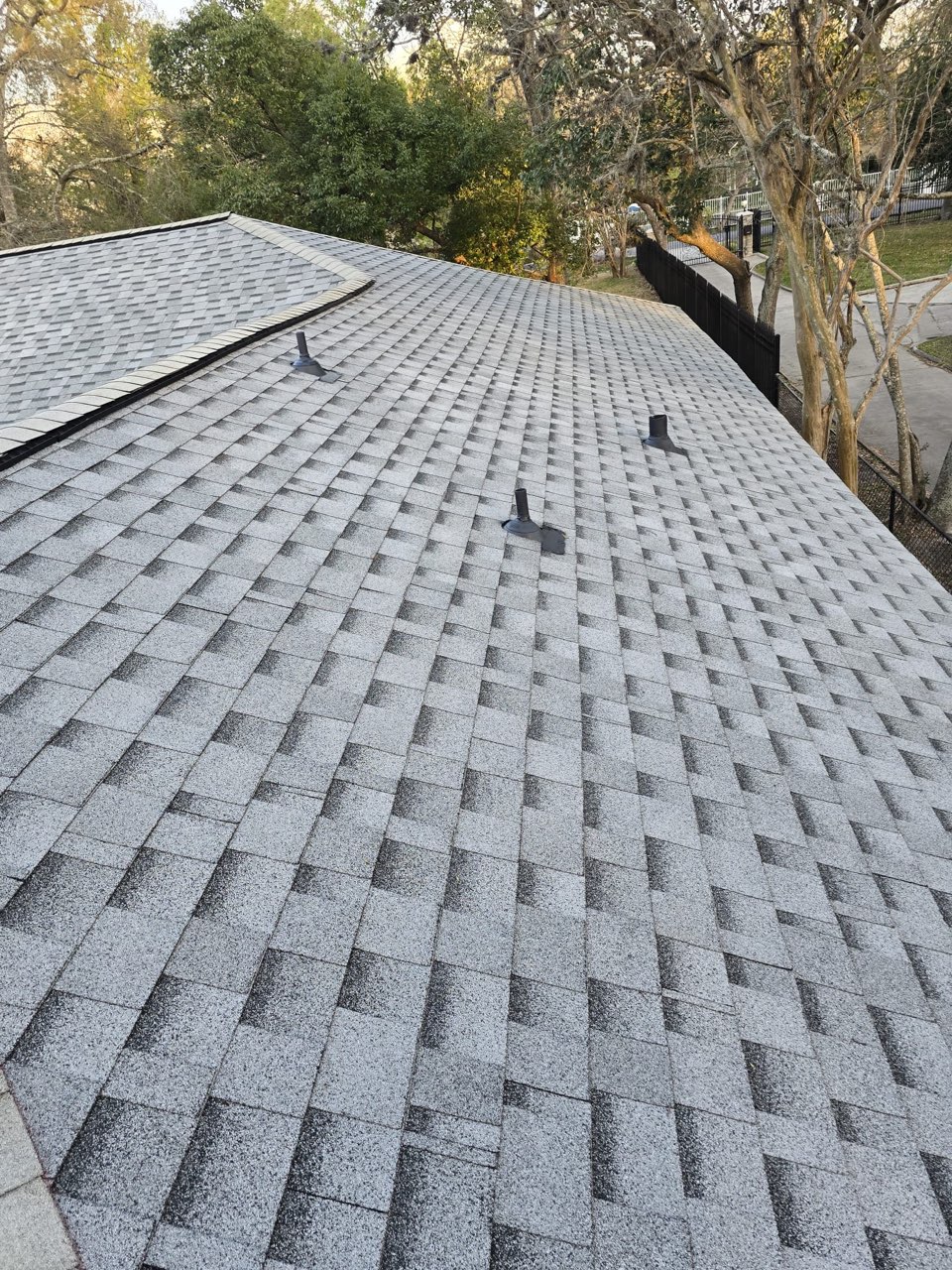 Grey asphalt shingle roof with pipe vent boots, viewed up the slope.